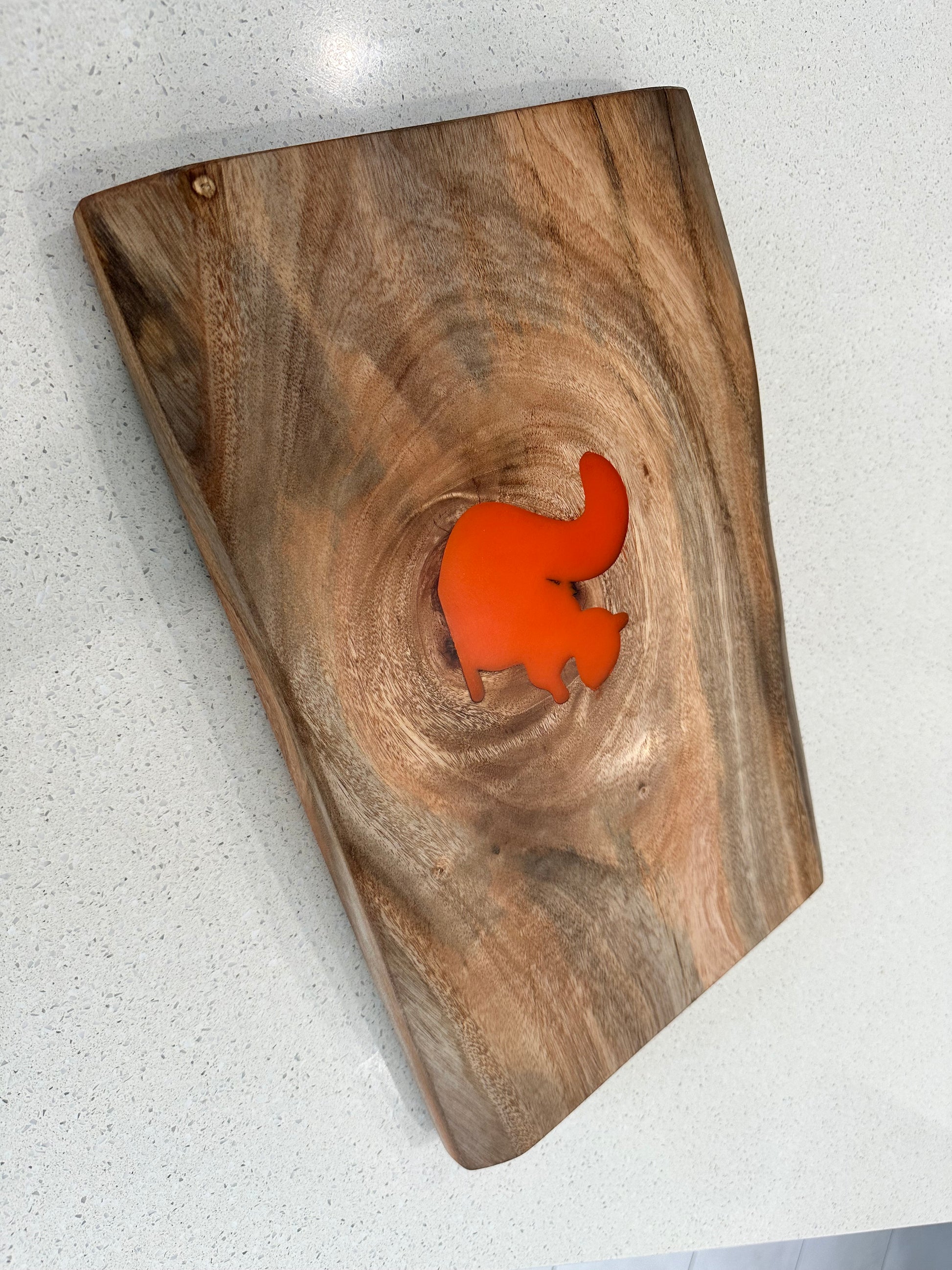 A Figured Hardwood Charcuterie Board with an orange squirrel resin inlay, positioned on a white surface.