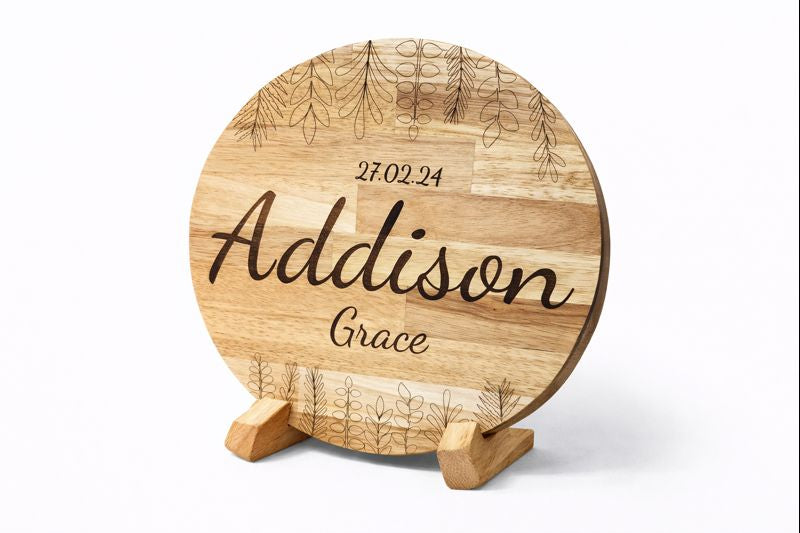 Personalised round wooden plaque featuring the name Addison Grace and birth date 27 February 2024 with botanical engravings.